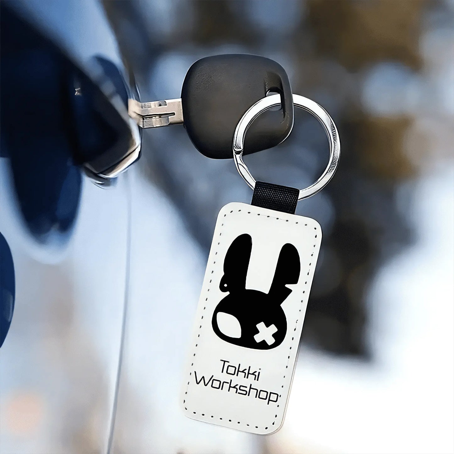 Keychain with sign design and 'Tokki Workshop' text, held by a gloved hand.