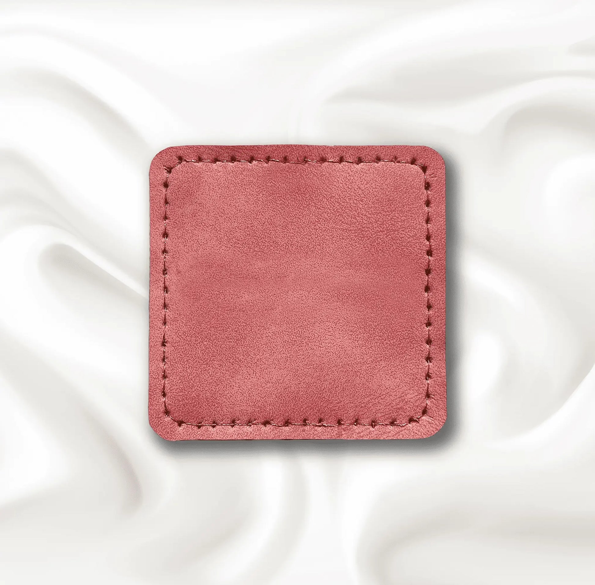 Pink square patch with stitching on a white fabric background.
