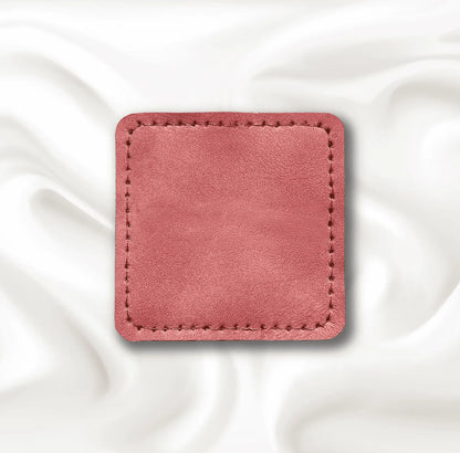 Pink square patch with stitching on a white fabric background.