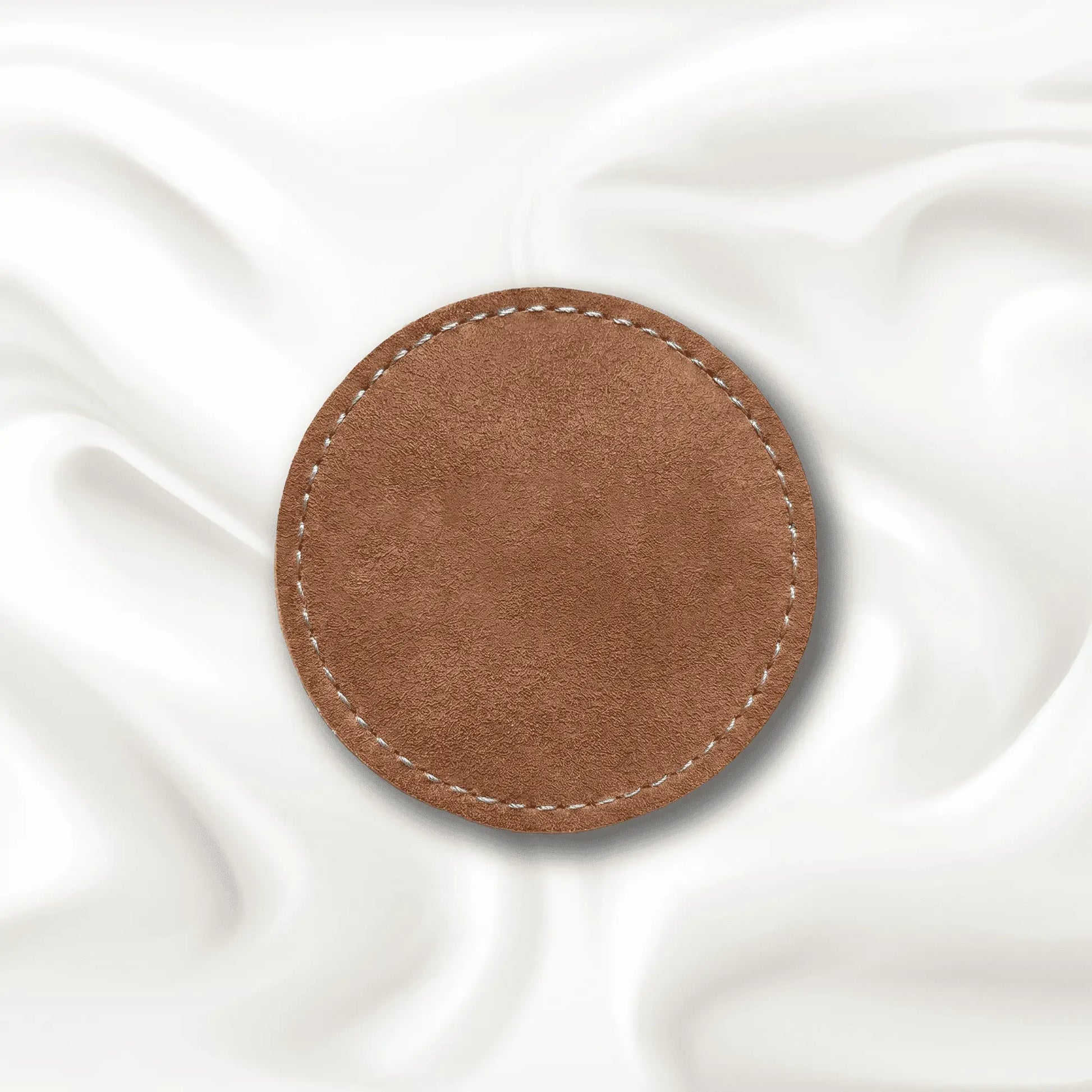 Brown circular leather patch on a white fabric background