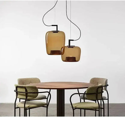 Danish glass pendant light illuminating a dining table with modern chairs in a minimalist setting.
