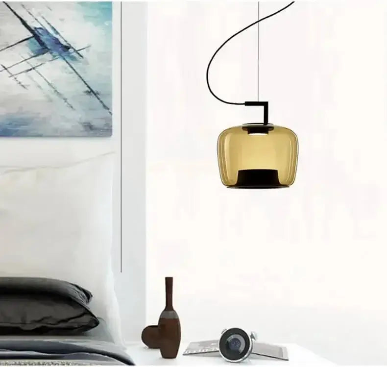 Danish glass pendant light hanging above a modern bedroom decor, featuring a sculptural silhouette.