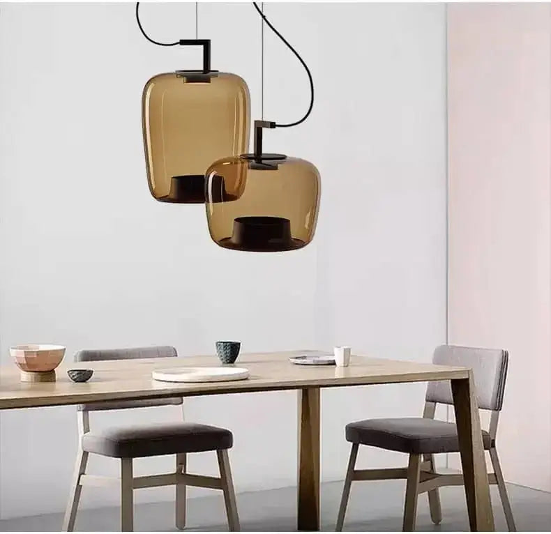 Danish glass pendant light hanging above a modern dining table, featuring sculptural silhouettes and a contemporary design.