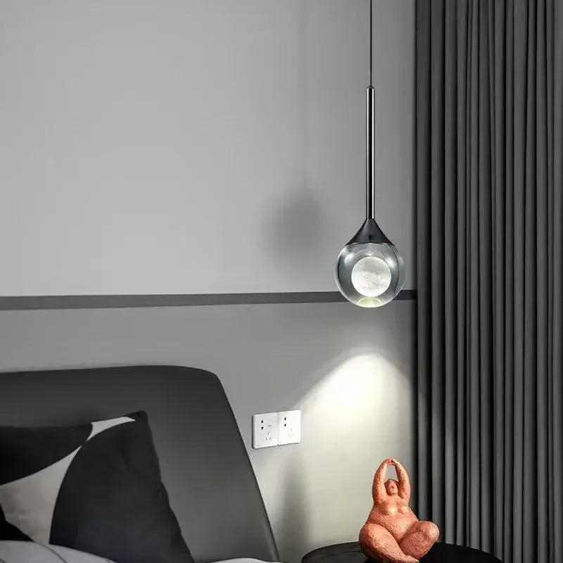 Modern Art Moon Pendant hanging above a bed in a bedroom setting.