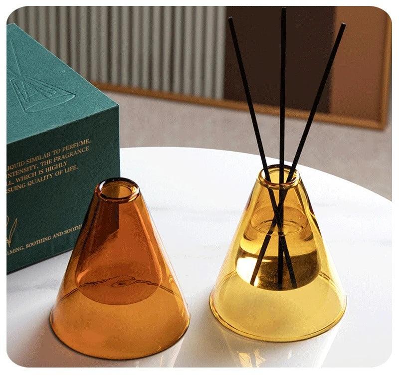 Two cone-shaped diffusers, one gold and one amber, on a white surface with a blurred background.