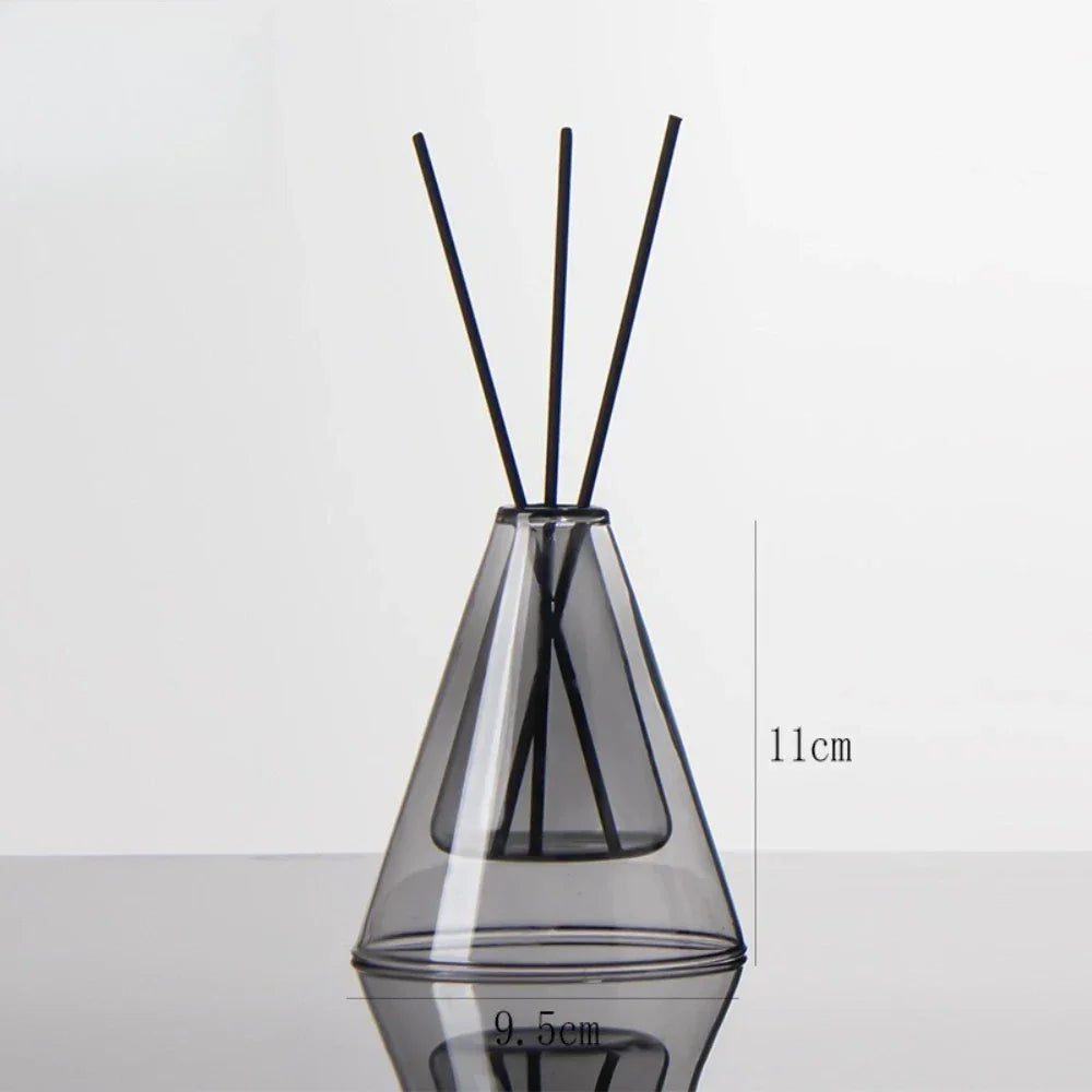 Clear glass diffuser vase with black sticks on a white background